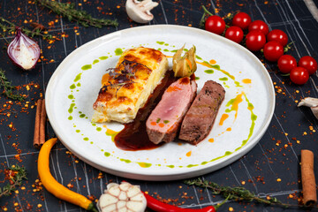 Plate with tender duck breast, potato gratin and various vegetables