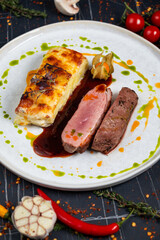 Plate with tender duck breast, potato gratin and various vegetables