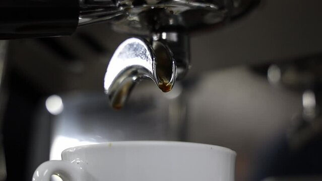 Closeup footage of a double shot espresso machine filling a white cup against blur background