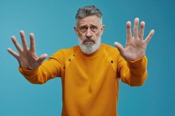 Naklejka premium Mature man showing stop gesture expressing fear and defense.