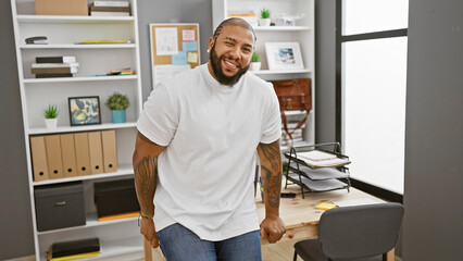Handsome black man with beard smiling in modern office wearing casual attire