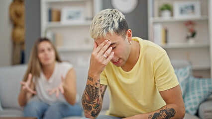 Beautiful couple sitting on sofa arguing at home