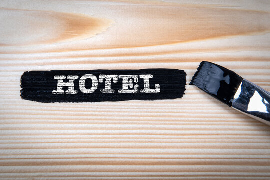Hotel. Black paint and paint brush on wood texture background