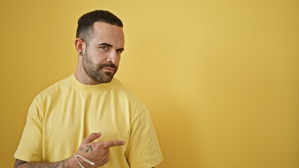 Hispanic man with beard in yellow t-shirt posing against solid yellow background, exudes casual...
