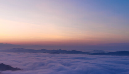 Un mare di nebbia e nuvole al tramonto riempie le valli sotto le montagne - obrazy, fototapety, plakaty