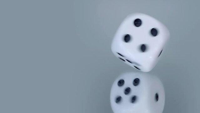 The dice spins on a mirror surface, describing circles. Will fate bring you luck in gambling. Closeup. Macro. Slow mo, slo mo, slow motion, high speed camera, 240fps, 250fps