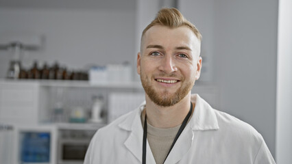 Fototapeta premium Handsome young man with beard smiling in white lab coat at a modern clinic