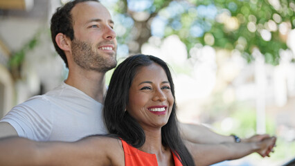 Fototapeta premium Beautiful couple standing together with arms open smiling at street