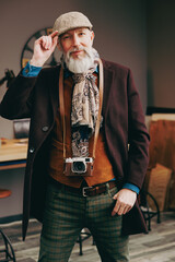 Portrait d'un photographe créatif et original  de type hispter très élégant et stylé avec un manteau un béret et un gilet dans un atelier créatif - 764953221