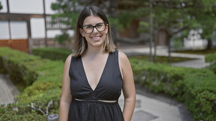 Joyful and confident, a beautiful hispanic woman in glasses stands by the serene ginkaku-ji temple,...