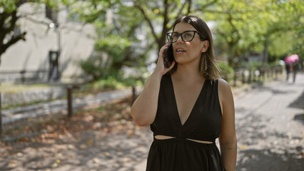 Gorgeous hispanic female in glasses joyfully speaking on smartphone, exuding confidence and happiness on a traditional kyoto street