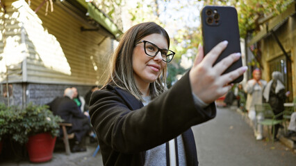 A young brunette woman takes a selfie on an urban istanbul street, showcasing travel and city life.