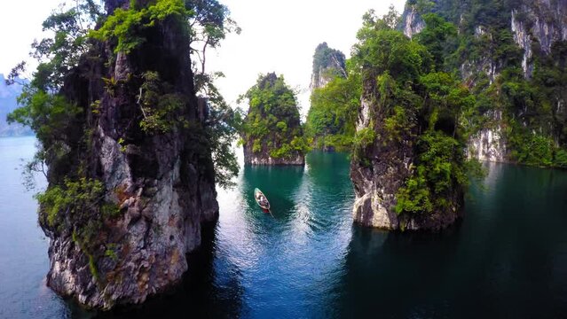 Aerial: Drone Forward Shot Of Tourists In Rowboat Moving On Cheow Lan Lake Amidst Rock Formations Against Clear Sky - Krabi, Thailand