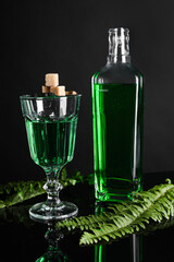 Absinthe, brown sugar, spoon and green leaves on mirror table. Alcoholic drink