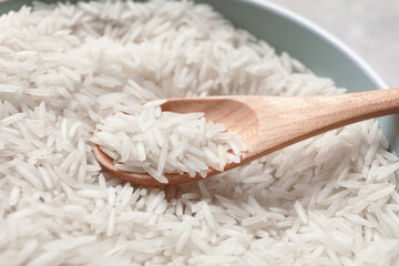 Raw basmati rice in bowl and spoon, closeup