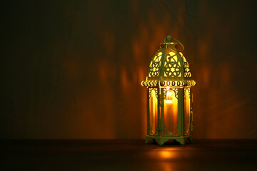 Decorative Arabic lantern on table against dark background. Space for text