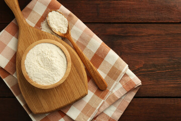 Baking powder in bowl and spoon on wooden table, top view. Space for text