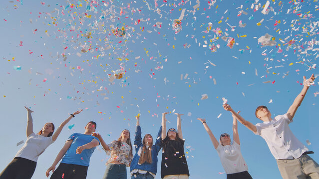 Friends toss colorful paper confetti from their hands.