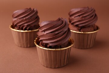 Delicious chocolate cupcakes on brown background, closeup