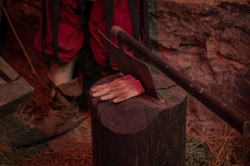 A severed hand by the executioner's ax on a log in the torture chamber. - obrazy, fototapety, plakaty
