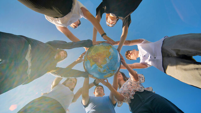 Friends holding a geographical globe in their hands. The concept of keeping the world safe.