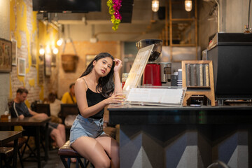 A young woman is sipping a cold alcoholic drink. While sitting at the bar in a rustic cafe and...