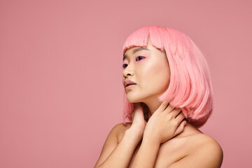 portrait of alluring woman with pink hair touching neck with hands on vibrant background
