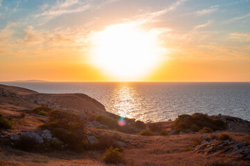 Sunset Seascape. Rocky seashore with yellow sun-scorched grass and a beautiful sky. Travel and tourism.