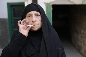 Senior Islamic woman smoking a cigarette 