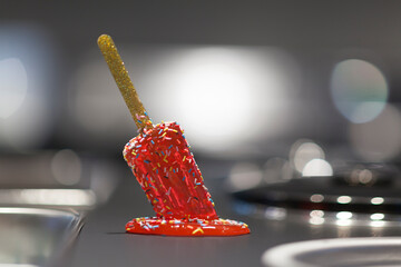 Close up on a melted popsicle on the iron table of a ice cream maker. - 764998435