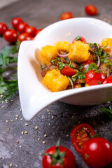 Grilled chicken cheese salad with tomatoes, onions and dill in a white bowl