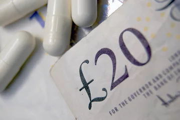 Gartenposter Currency and pills.  UK pounds bank notes. © Richard