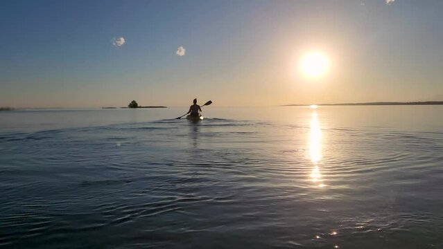 Women's silhouette rowing in kayak at sunset. Video 4k