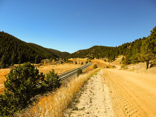 Scenic View of a Dirt Road and Train Tracks Through the Valley Between the Mountains Under a Clear Blue Sky