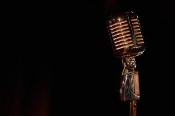 Close up of retro microphone on stage with black background copy space