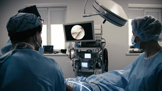 Professional surgeons perform the operation in a modern surgical operating room and monitor the process in front of monitors. Modern medical technologies, operation and surgery department.