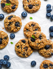 Gluten free blueberry oatmeal cookies on a white baking paper. Served with fresh blueberries.