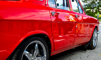 A close-up view of a red vintage car from the side.