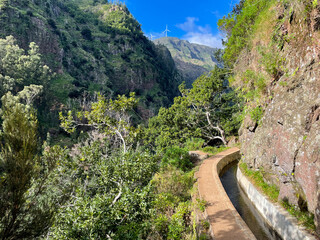Obraz premium Stunning view of the beautiful hiking trail Levada do Moinho on a sunny day on Madeira island, Portugal