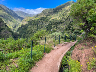 Stunning view of the beautiful hiking trail Levada do Moinho on a sunny day on Madeira island,...
