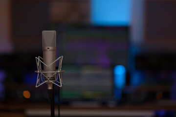Close up on a high end studio microphone, background is a blurred studio environment, no people are visible. - 765025685