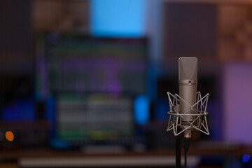 Close up on a high end studio microphone, background is a blurred studio environment, no people are visible. - 765025695