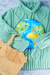 The sweater sleeves holding the tags in the embrace of the planet with an eco bag. Responsible...