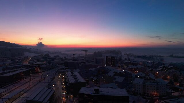 Drohnenaufnahme eines Sonnenuntergangs im Winter in Rotkreuz (Kanton Zug). Die Landschaft ist mit Schnee bedeckt. 