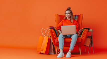 Full length portrait of a happy young woman sitting in armchair with laptop and shopping bags on Coral color background professional photography.