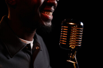 Close up of smiling Black man speaking to microphone on stage performing in comedy show copy space