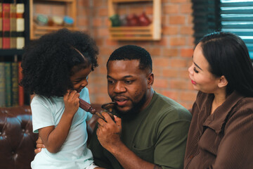 Smiling African-American father shares fun and love with his cheerful children at home, celebrating family with childhood together, African American black person in happy together of father's day - obrazy, fototapety, plakaty
