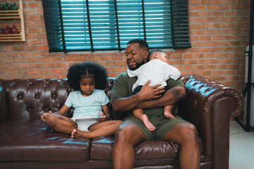 Smiling African-American father shares fun and love with his cheerful children at home, celebrating family with childhood together, African American black person in happy together of father's day - 765031653