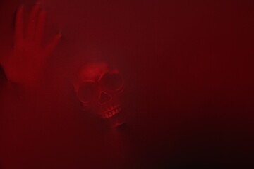 Silhouette of creepy ghost with skull behind red cloth. Space for text