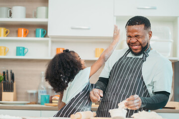 In a home kitchen, black father and his daughter bond over cooking a meal food, their laughter and love filling the air, embodying the joy of African American family life, Father's Day concept - 765031838